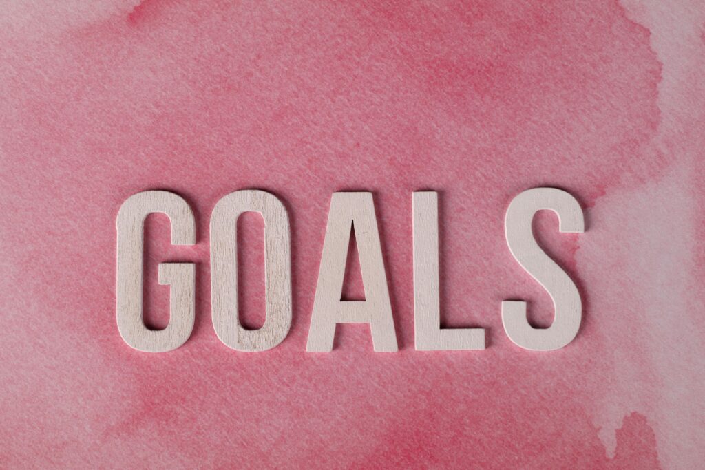Motivational word 'GOALS' on a pink watercolor background for inspiration.