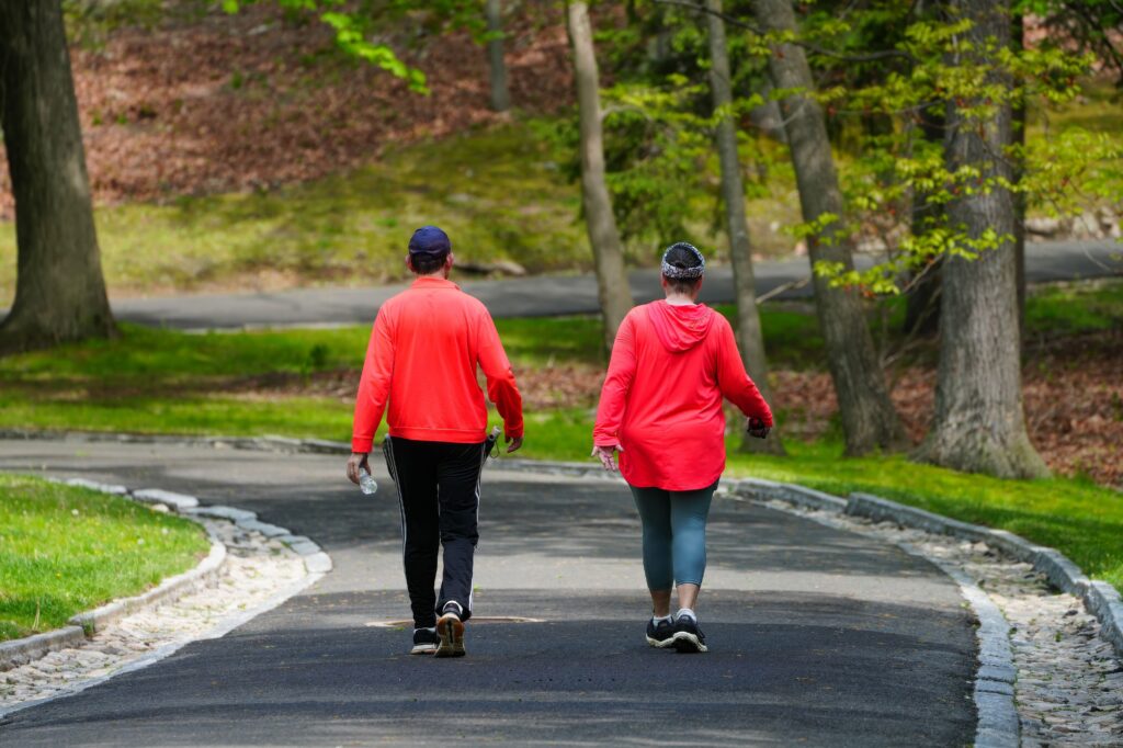 How Many Steps a Day Do You Really Need to Lose Weight? A couple enjoys a walk through a lush green park on a bright spring day.
